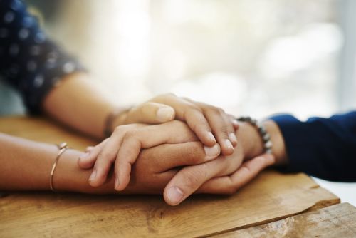 Closeup of two people clasping hands concept for: Should You Get a Revocable Living Trust?