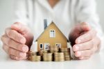 Woman's hands protecting on stack coins and house model on table. Visual concept for a bankruptcy blog discussing 