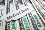 Medical Debt message on torn paper laying on a line of hundred dollar bills