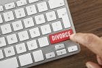 Man's index finger pushing red “Divorce” key on computer keyboard.
