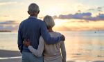 Elderly couple spending time on the beach, gently hugging each other, looking at the sunset,visual concept for transfer on death and estate planning.